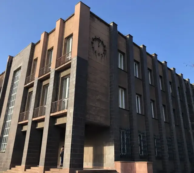 Imponujący budynek w stylu modernizm architektura, z ciemnymi płytkami i jasnymi akcentami, ozdobiony zegarem.