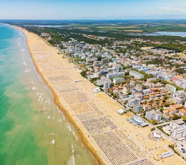 Słoneczna bibione plaża tętni życiem. Tysiące leżaków i parasoli tworzą barwny dywan na piasku, a turkusowe morze zaprasza do kąpieli.