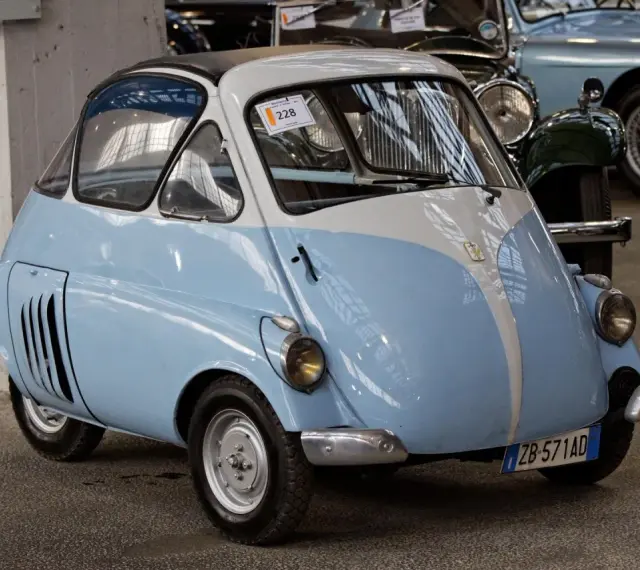 Urocze, błękitno-białe BMW Isetta z lat 50. z charakterystycznymi drzwiami z przodu, gotowe na przejażdżkę po mieście.
