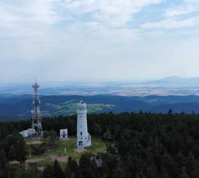 Wieża widokowa niczym wielka sowa, ile się wchodzi, góruje nad lasem. Obok maszt telekomunikacyjny.
