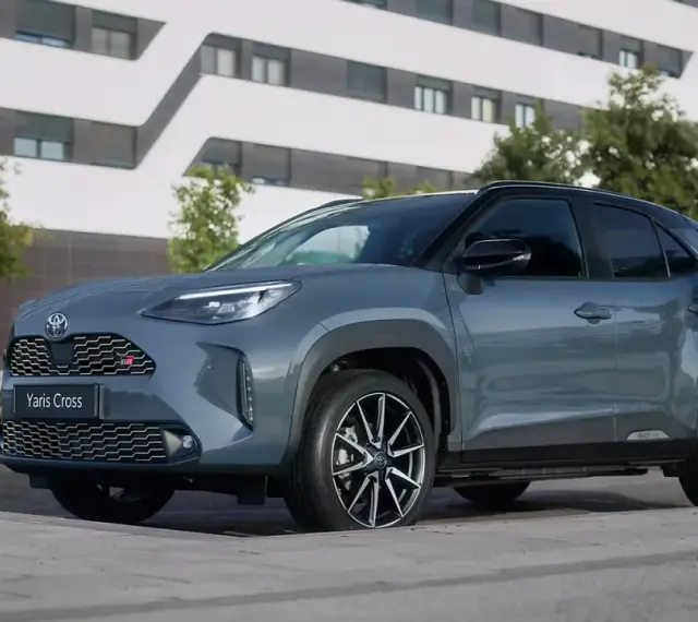 Szary Toyota Yaris Cross hybryda stoi na tle nowoczesnego budynku.