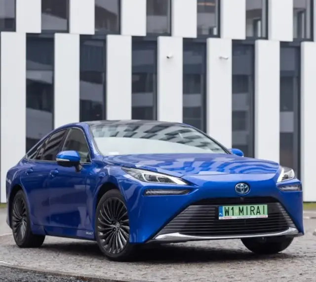 Niebieski samochód Toyota Mirai na tle nowoczesnego budynku.