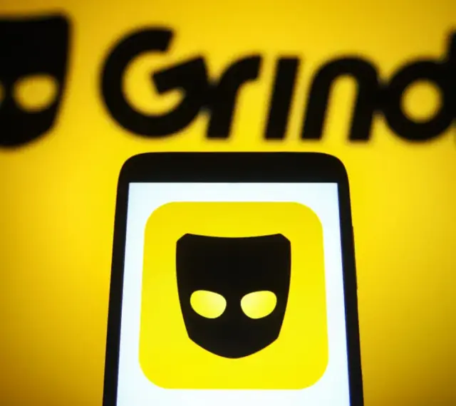 Ikona aplikacji Grindr na ekranie telefonu, na tle logo Grindr.