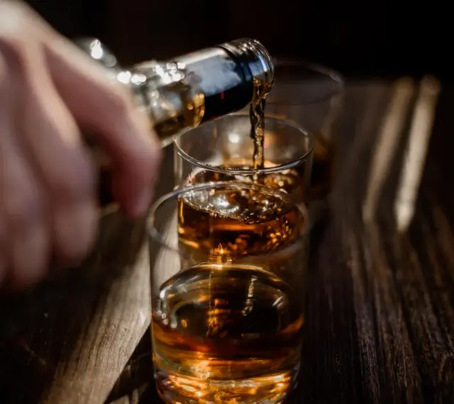 Nalewanie alkoholu do szklanek. Ta scena może symbolizować sprawę w sądzie za picie alkoholu przez nieletnich.