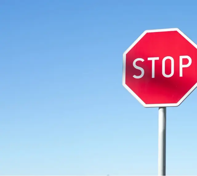 Czerwony znak STOP na tle błękitnego nieba. Uważaj, by nie dostać mandatu za stop!
