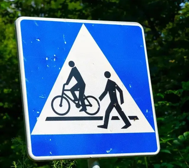 Znak ostrzegawczy: przejazd rowerowy i przejście dla pieszych. Czy rowerzysta ma pierwszeństwo na przejeździe rowerowym? Tak, ten znak informuje o tym.