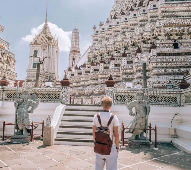 Młody turysta z plecakiem podziwia majestatyczną świątynię Wat Arun w Bangkoku. Czy Bangkok jest bezpieczny? Tak, zwłaszcza w takich pięknych i spokojnych miejscach.