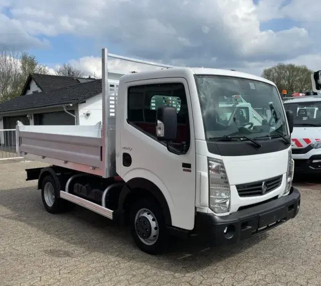Biały Renault Maxity z otwartą skrzynią ładunkową stoi na placu. W tle budynek i inne pojazdy.