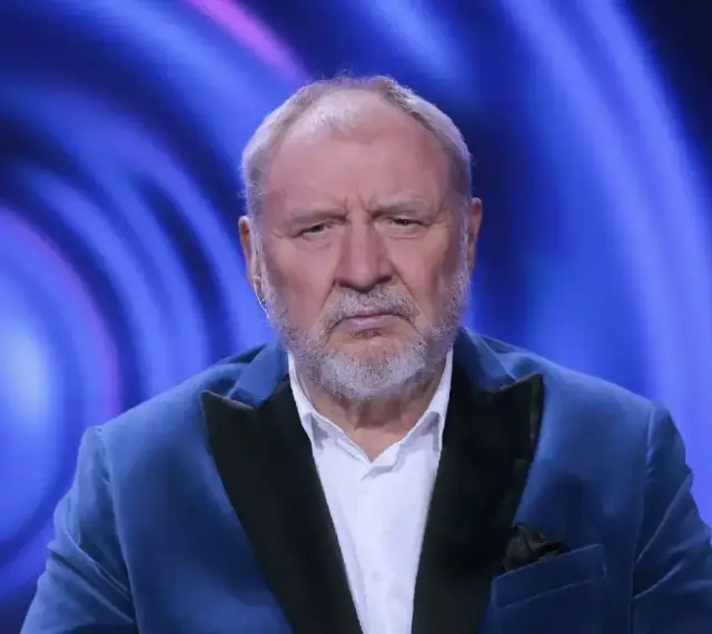 Andrzej Grabowski żyje i wygląda na zmęczonego, siedząc w niebieskiej marynarce na tle niebieskich świateł.