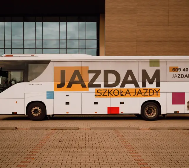 Biały autobus szkolny z napisem "JAZDAM SZKOŁA JAZDY" i numerem telefonu. Idealny do nauki jazdy kategorii D.