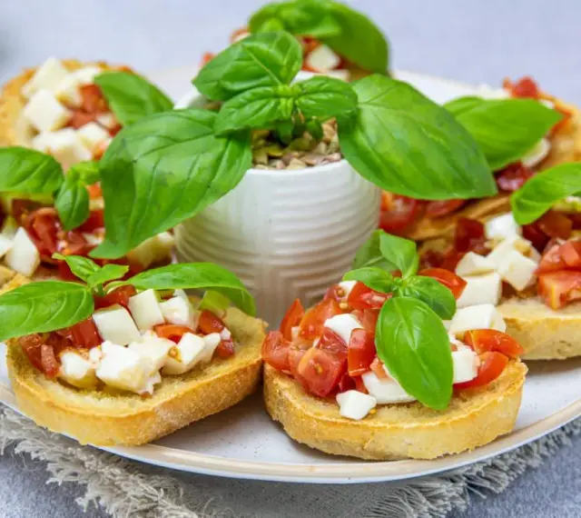 Bruschetta z pomidorami i mozzarellą – pyszny przepis na letnią przekąskę. Chrupiące grzanki z dodatkiem świeżej bazylii.
