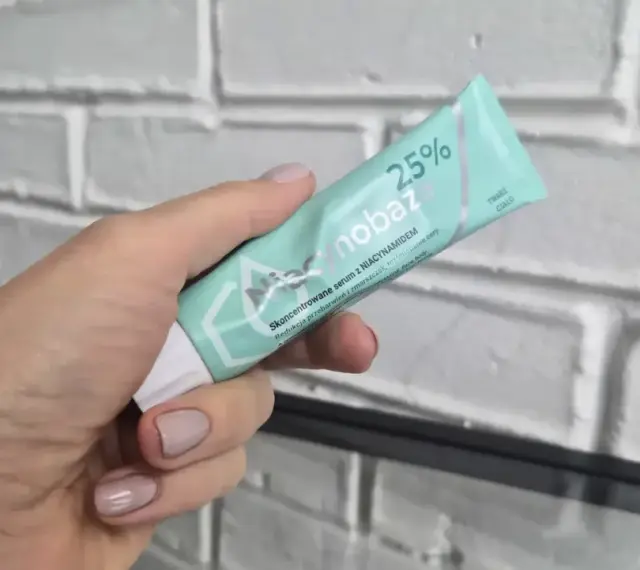 Dłoń trzyma tubkę serum niacynobaza 25%. Wiele pozytywnych opinii o tym produkcie.