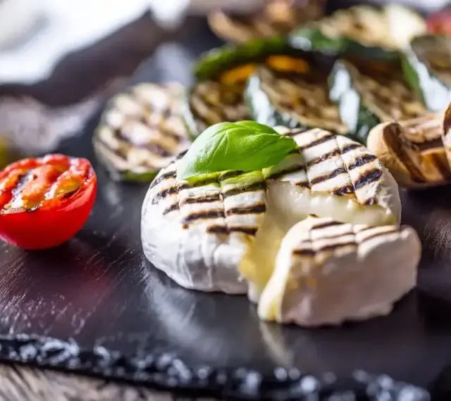 Pyszny camembert z grilla, z rumianymi paskami, podany z grillowanymi warzywami i pomidorkiem. Idealny na letnie wieczory.