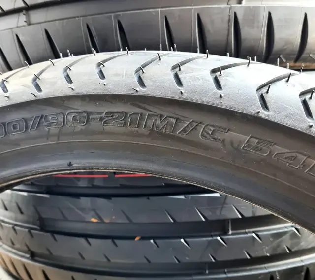 Opona motocyklowa z oznaczeniem 90/90-21M/C 54H. Szerokość opony jest kluczowa dla przyczepności.