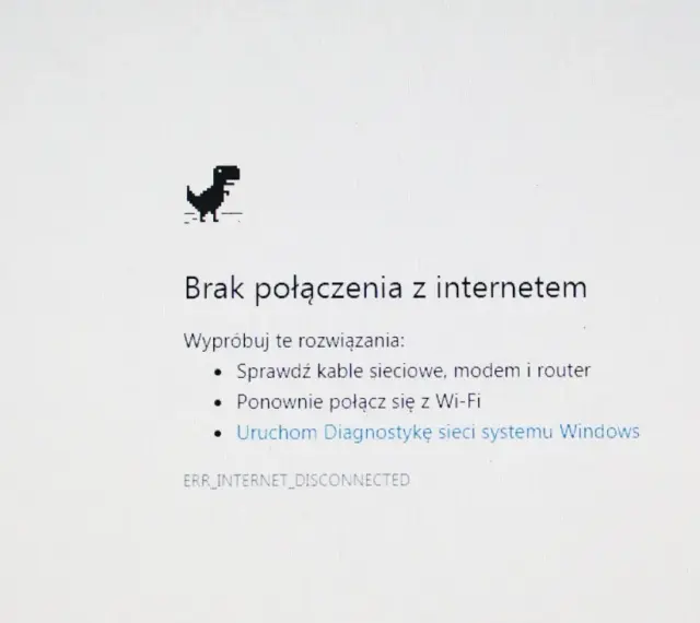 Dinozaur z gry Chrome skacze, bo jest brak internetu. Komunikat "Brak połączenia z internetem" sugeruje sprawdzenie kabli i ponowne połączenie z Wi-Fi.