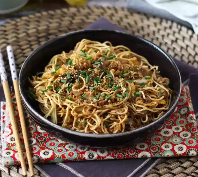 En skål med nudlar, köttfärs och grönsaker, toppad med sesamfrön och gräslök. Ett perfekt wok recept för en snabb middag.