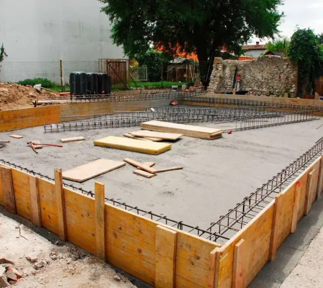 Drewniane szalunki i zbrojenie czekają na beton, tworząc fundamenty z kamienia.