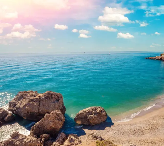 Piękne wybrzeże Costa del Sol z białymi domkami na klifie, turkusowym morzem i skalistą plażą. Idealne miejsce na wakacje!