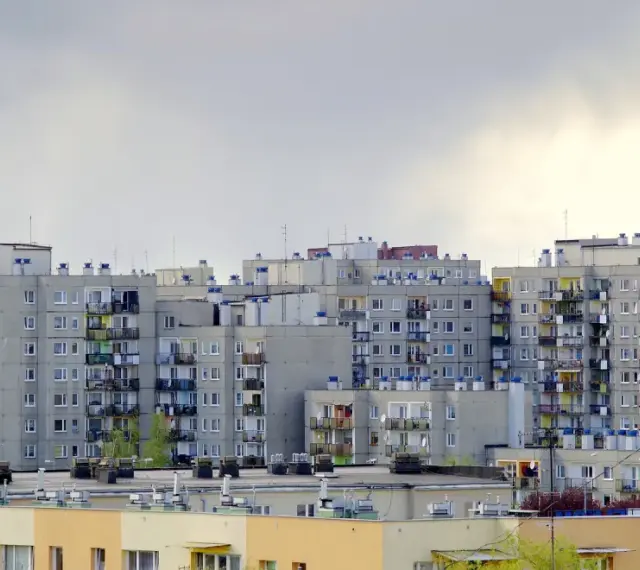Bloki z cegły, dlaczego w 2026 roku mieszkania w blokach z cegły drożeją szybciej niż te z płyty? Szare, wielopiętrowe budynki mieszkalne z balkonami.