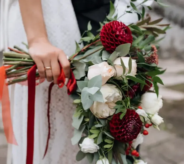Elegancki bukiet z czerwonych i białych kwiatów, ozdobiony wstążkami, idealny jako kwiaty na ślub w prezencie.