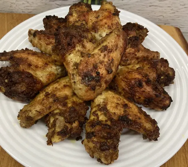 Chrupiące skrzydełka z airfryer ułożone na białym talerzu, apetycznie przypieczone i gotowe do podania.