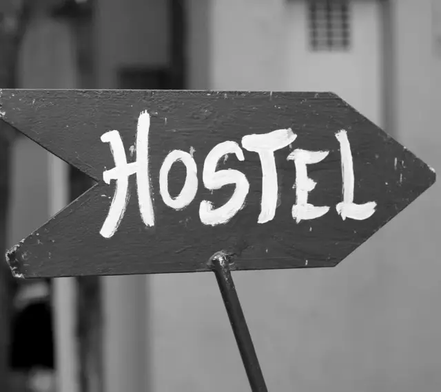 Strzałka z napisem "Hostel" wzywa podróżnych do taniego noclegu. To miejsce, gdzie poznasz innych wędrowców.