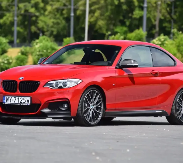 Czerwone BMW f23 coupe z czarnymi dodatkami i felgami stoi na asfalcie.