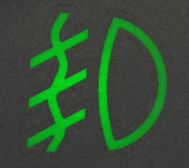 Zielony symbol świateł mijania na ciemnym tle.