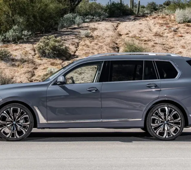 Szary BMW X9 na tle pustynnego krajobrazu. Elegancki SUV z chromowanymi detalami i masywnymi felgami.