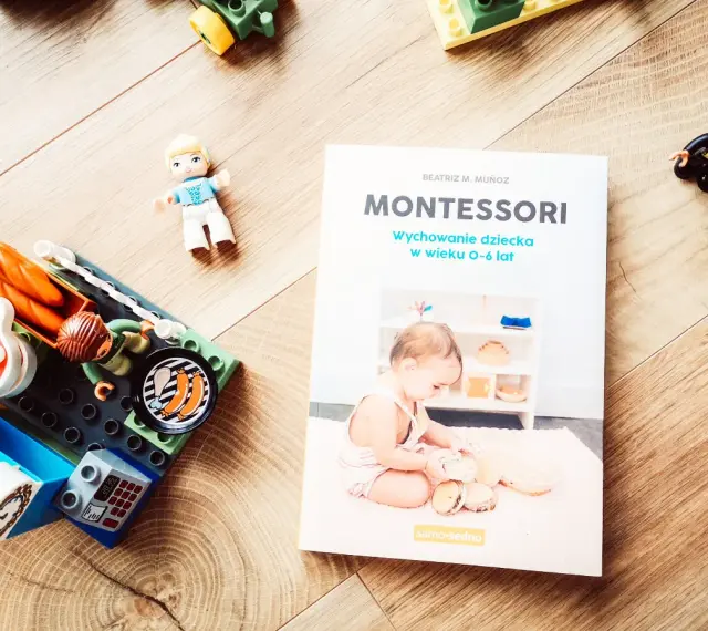 Książka "Montessori. Wychowanie dziecka w wieku 0-6 lat" obok klocków i figurek. Idealna do nauki przez zabawę.