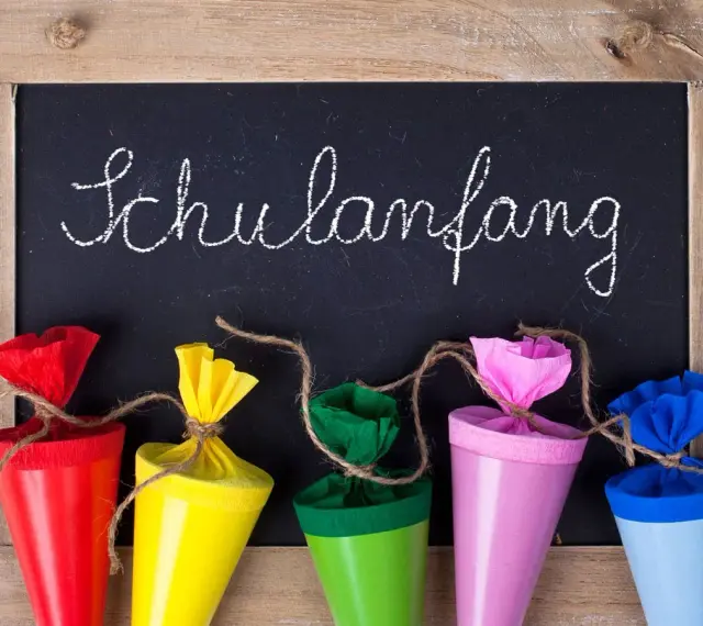 Bunte Schultüten vor einer Tafel mit "Schulanfang" für die Einschulung Hessen 2025.