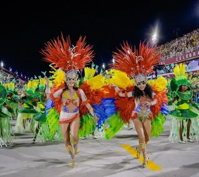 Tancerki w barwnych strojach z piórami na tle tłumu na **Rio de Janeiro karnawał**.