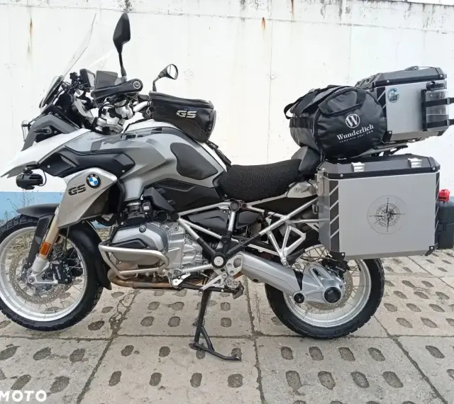 Srebrny motocykl BMW R1200GS z kuframi i torbą na bak. Wady tego modelu to m.in. wysoka cena i skomplikowana elektronika.