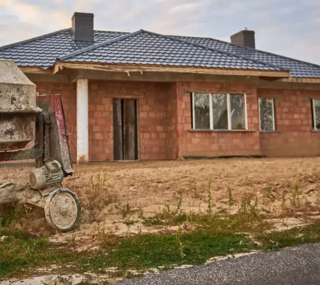 Dom w budowie, beton wylewany z betoniarki. To jeden z etapów budowy domu, który wpływa na kosztorys.