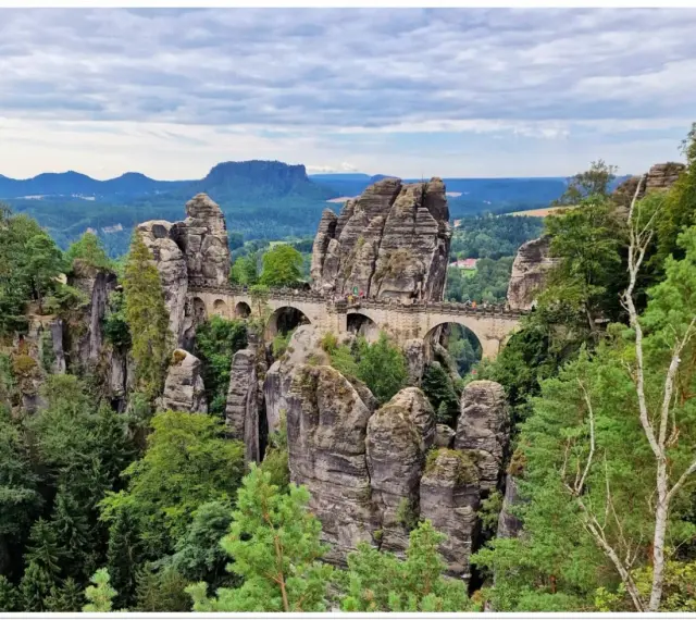 Kamienny most Basteibrücke w Szwajcarii Saksońskiej, łączący skalne baszty pośród zielonych lasów i gór.