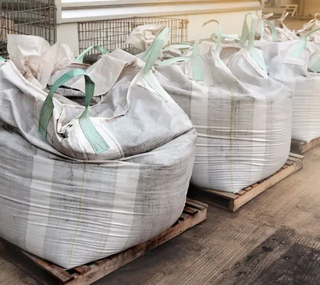 Rząd dużych worków big bag, każdy o pojemności ok. 1 m3, ustawionych na paletach.