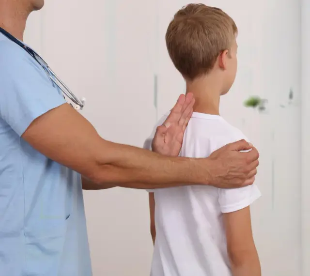 Lekarz bada chłopca, sprawdzając jego postawę. Może to być część diagnostyki zespołu Marfana objawy.