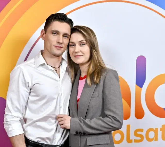 Małgorzata Patryn Gurłacz z partnerem pozują na tle kolorowego logo.
