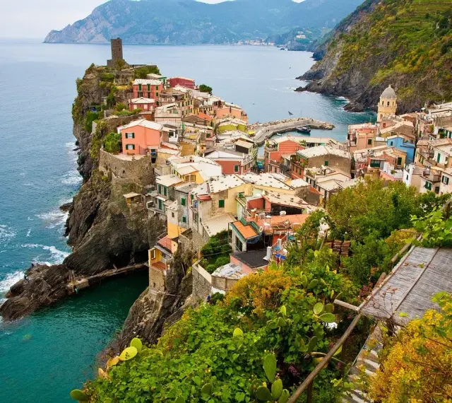 Kolorowe domy Cinque Terre na klifie, idealne na wakacyjne loty do Włoch.