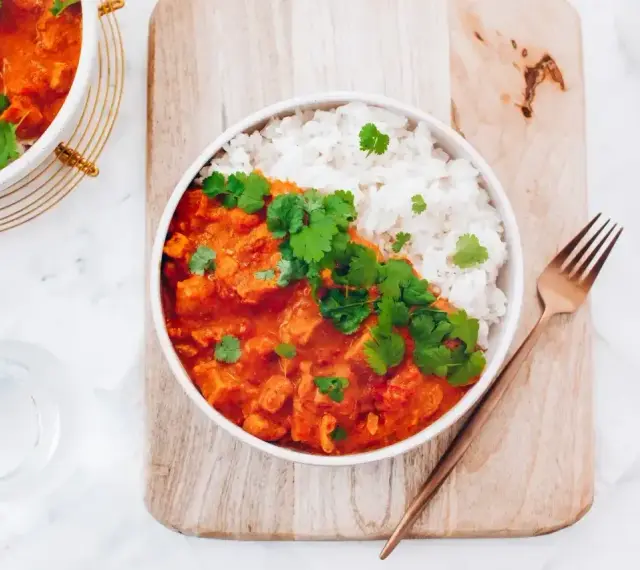 Pyszne czerwone curry z kurczakiem i ryżem, udekorowane świeżą kolendrą. Idealny przepis na obiad.