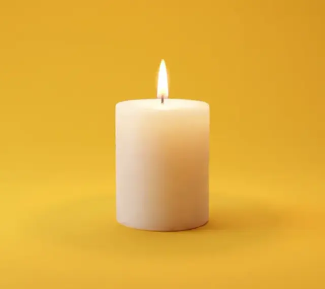 Brennende Kerze auf gelbem Hintergrund. Sie symbolisiert Hoffnung und Trost, was bei der Frage nach dem welcher pflegegrad bei palliativ wichtig ist.
