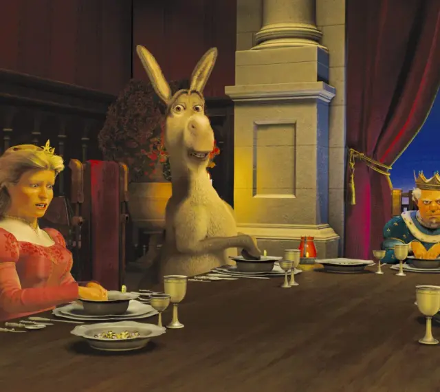 Królowa Fiona, Osioł i Król Harold siedzą przy stole. Scena z filmu DreamWorks.