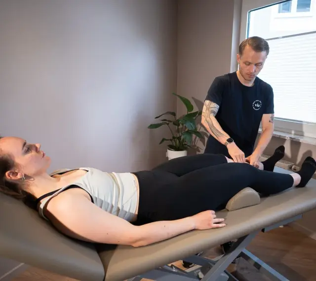 Therapeut führt Lymphdrainage am Bein einer liegenden Frau durch. Die Frage "wie lange dauert eine lymphdrainage" wird hier beantwortet.