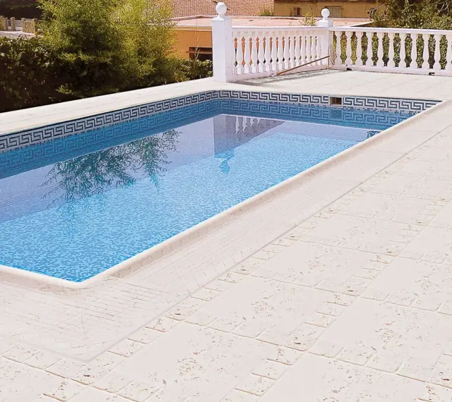 Piscina con borde de mosaico y suelos para piscinas que no quemen, de color claro y textura agradable.