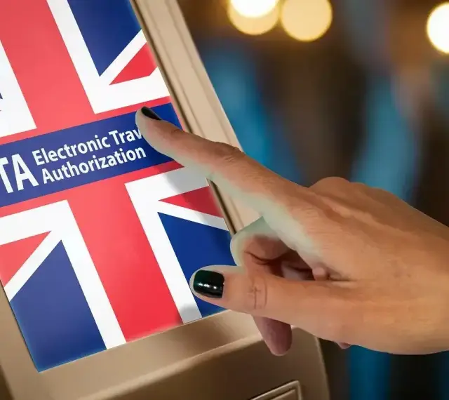 Dłoń dotyka ekranu z flagą Wielkiej Brytanii i napisem "ETA Electronic Travel Authorization". Czy do Londynu trzeba paszport? Sprawdź ETA.