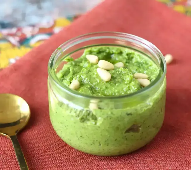 En burk med hemgjord pesto, toppad med pinjenötter. Perfekt för ditt nästa pesto recept!