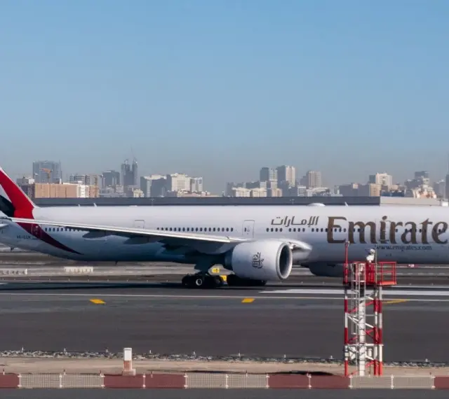 Samolot Emirates na płycie lotniska, w tle panorama Dubaju. Zastanawiasz się, ile się leci do Dubaju?