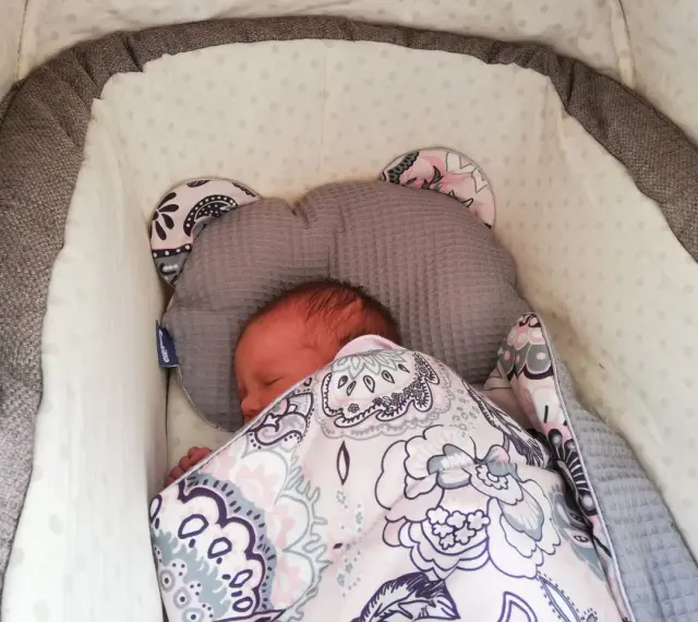 Malutkie dziecko śpi w wózku, otulone kolorowym kocykiem. To pierwszy spacer, czas na drzemkę.