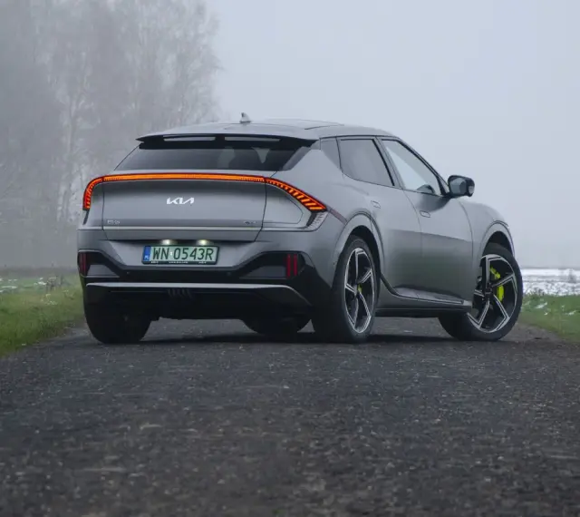 Szare Kia EV6 GT z żółtymi zaciskami hamulcowymi na tle mglistego krajobrazu.