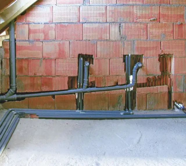 Instalacja hydrauliczna w trakcie budowy. Widoczne rury odprowadzające, pion sanitarny z odpowietrzeniem zgodnym z normą.